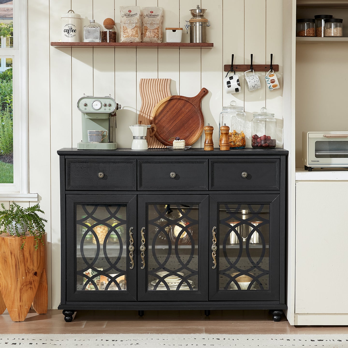 Black buffet cabinet with drawers above three glass door compartments and curved metal pulls