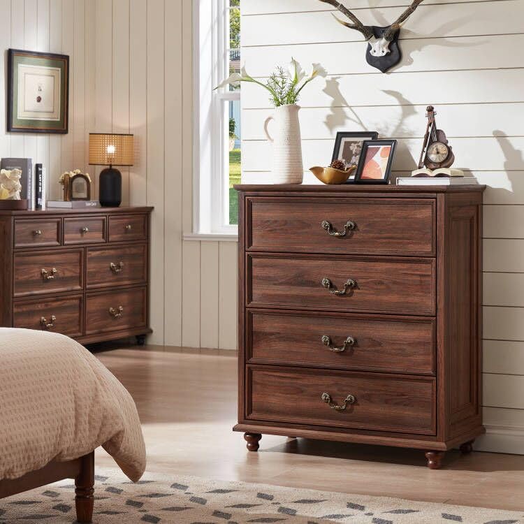 Dark wood dresser with multiple drawers, ornate metal handles, and rounded bun feet
