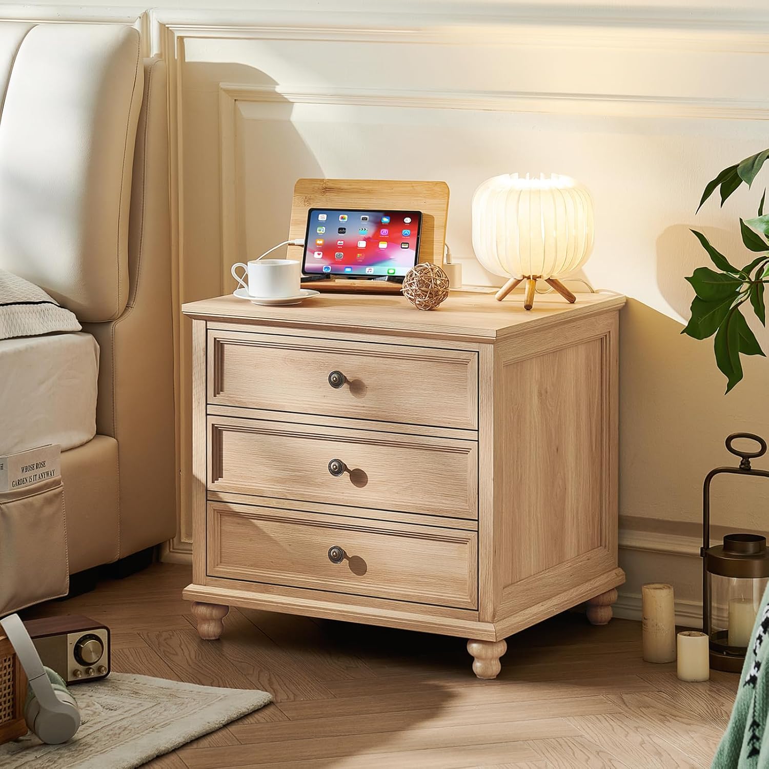 Farmhouse nightstand in light wood with three drawers and round metal knobs, bedside height.