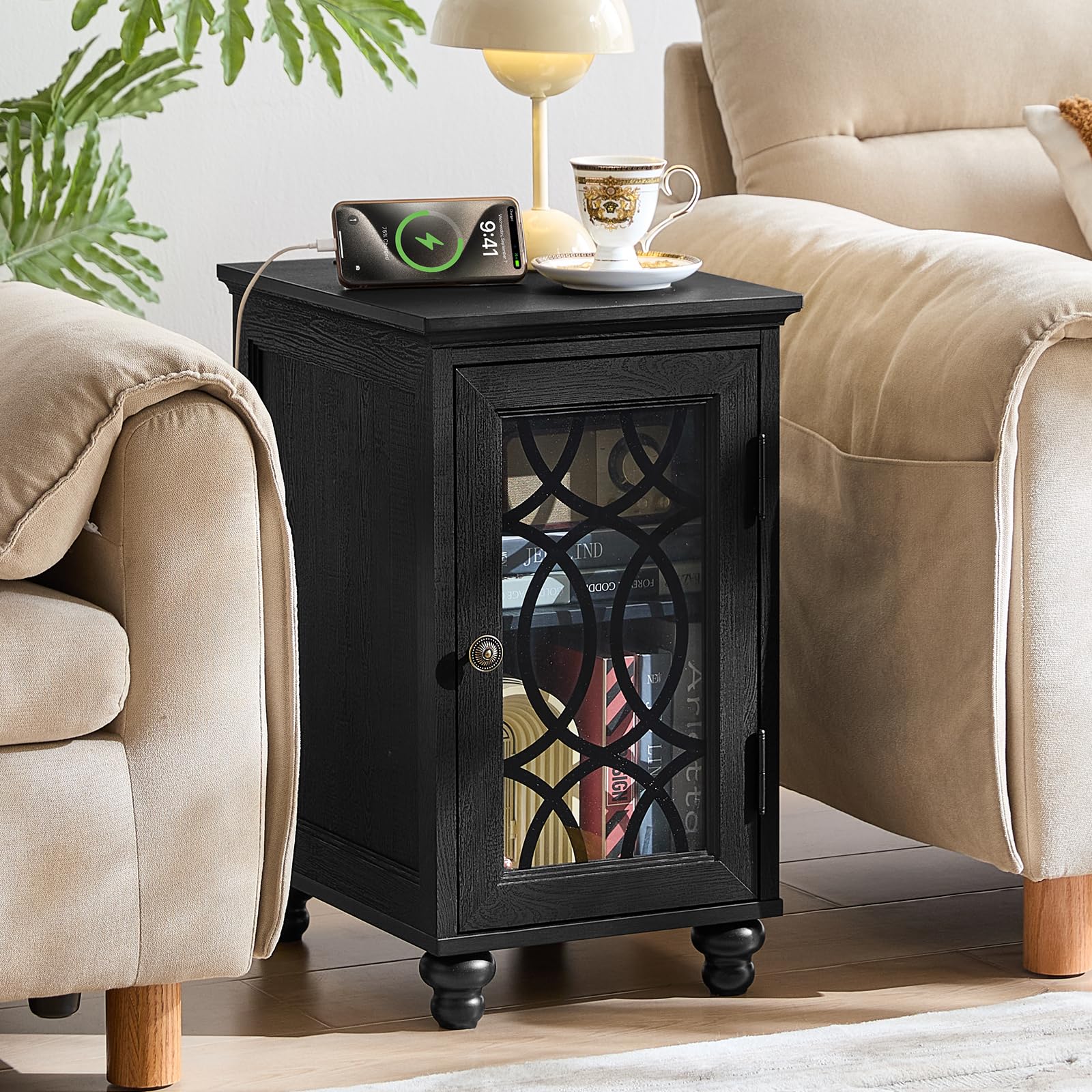 Black narrow nightstand with glass door and charging devices on top, turned feet