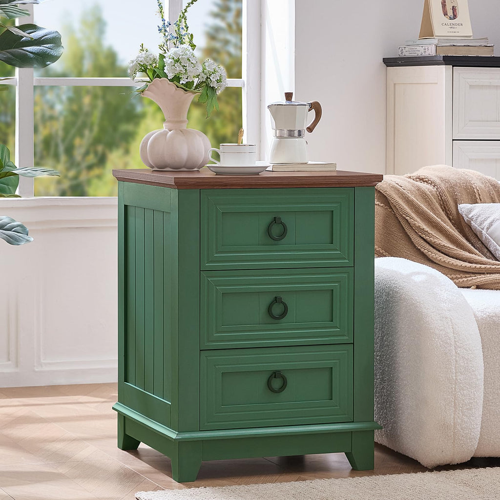 Green farmhouse nightstand cabinet with 3 drawers and round metal pulls next to bed.