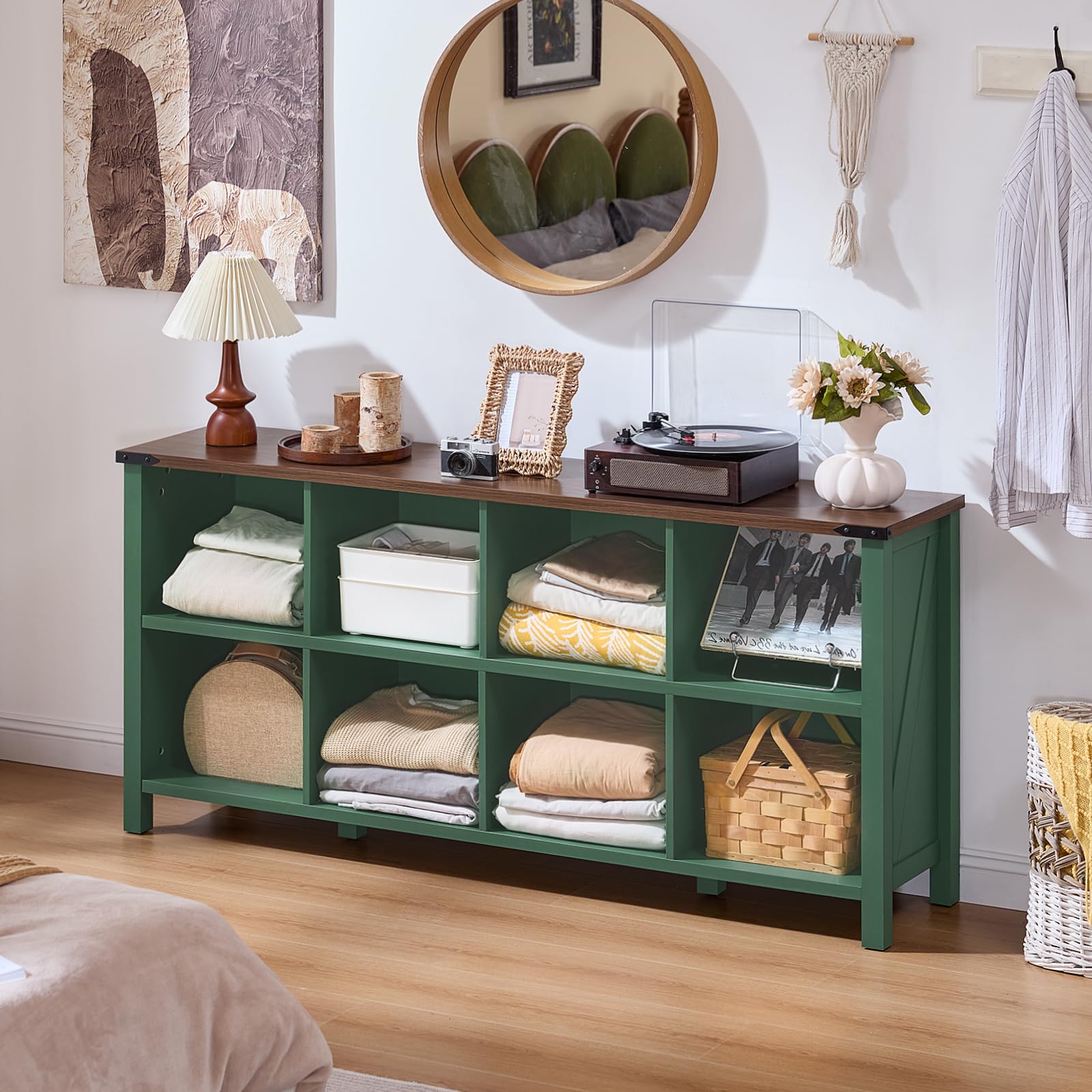 Green low storage bookcase with open cubbies and center drawer, topped with decor