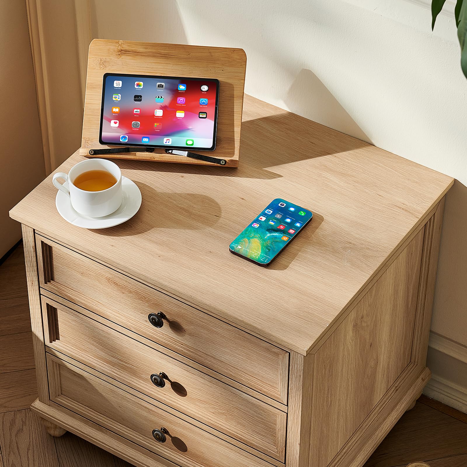 Light wood nightstand with three drawers and metal knob pulls