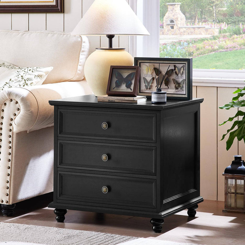 Black dresser with three drawers, round knobs, and turned wooden feet