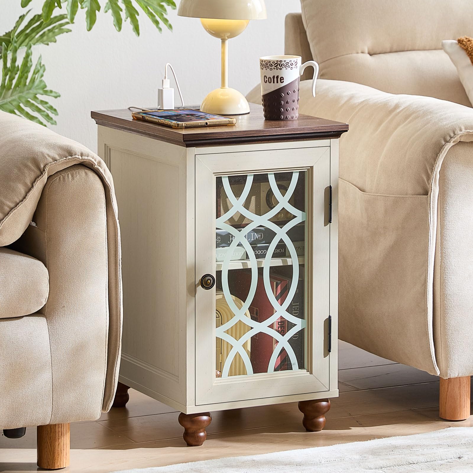 White bedside end table with glass cabinet door, dark handles, and charging cords