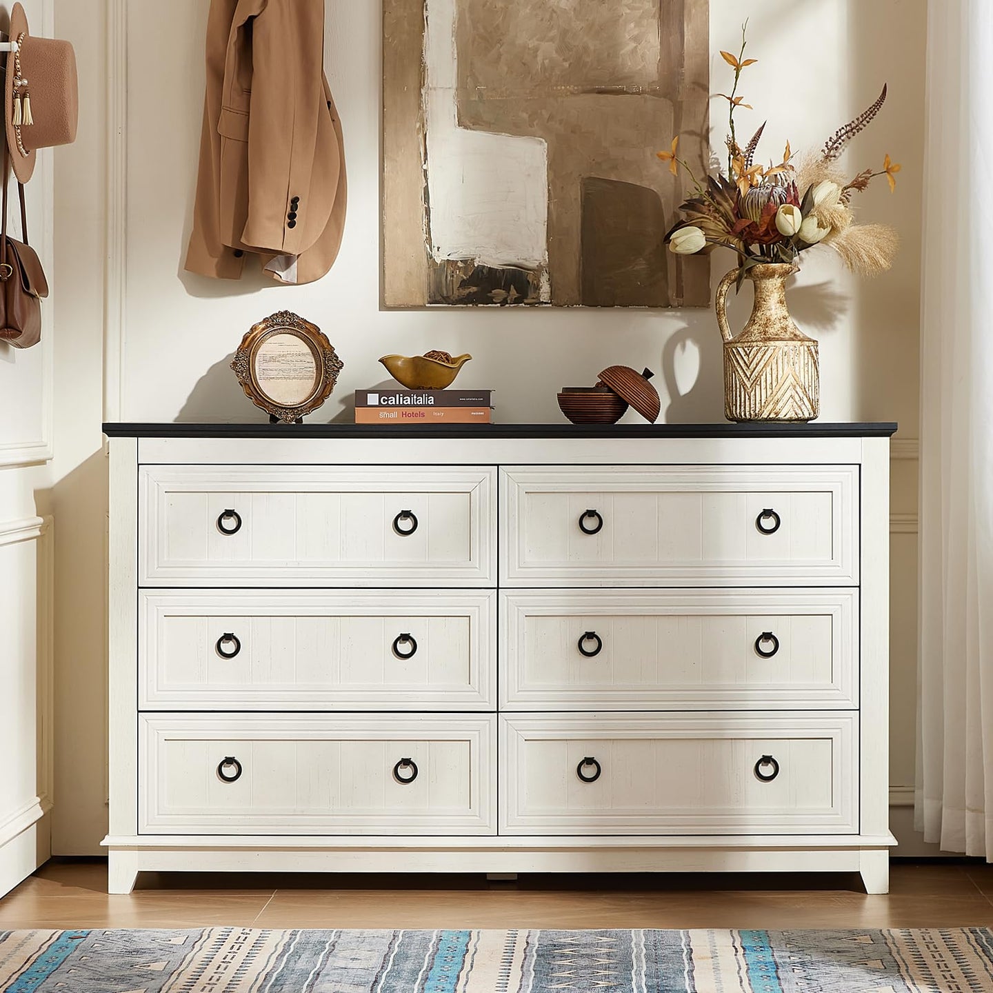 White wood dresser with six drawers and round metal knobs, front view with decorative items on top