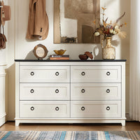 White wood dresser with six drawers and round metal knobs, front view with decorative items on top