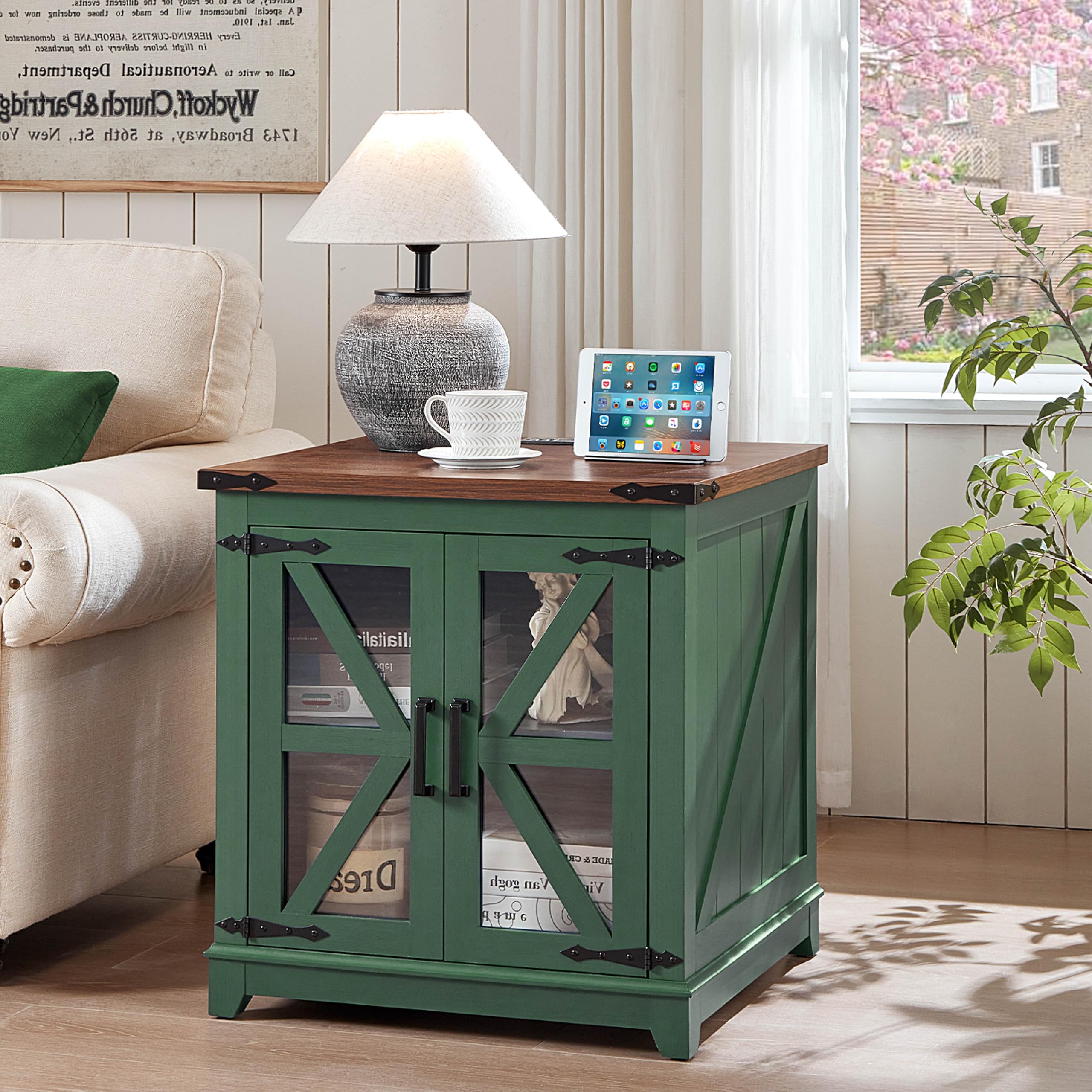Green farmhouse end table with glass barn doors and wooden top beside a sofa